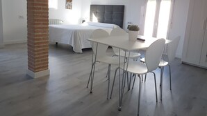 Un dormitorio moderno con una cama grande, una mesa de comedor con sillas y un pilar de ladrillo.
