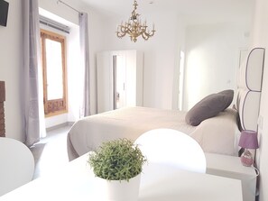 Un dormitorio moderno con una cama grande, una araña, una planta en maceta y vistas al exterior.