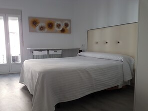 Un dormitorio con cama, escritorio y ventana.