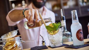 Un barman verse une boisson dans un verre rempli de glaçons et décoré d’une feuille de menthe.