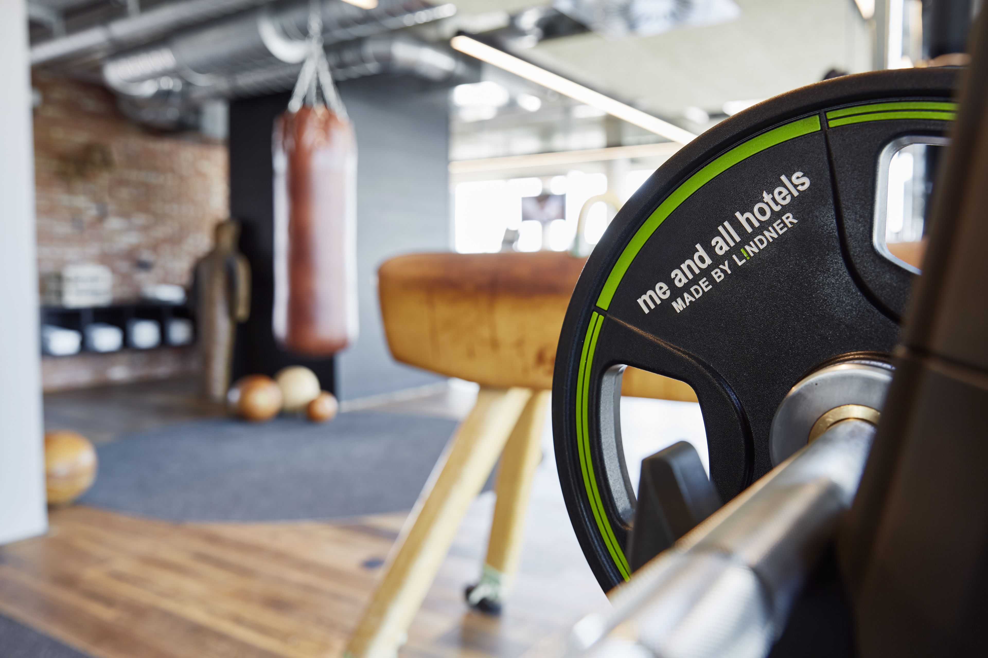 Une salle de sport équipée d’un banc de musculation, d’un sac de frappe et d’un tabouret en bois.