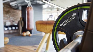 Une salle de sport équipée d’un banc de musculation, d’un sac de frappe et d’un tabouret en bois.