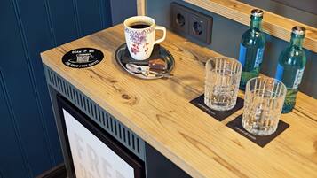 A wooden counter with a coffee cup, two glasses, and two bottles.