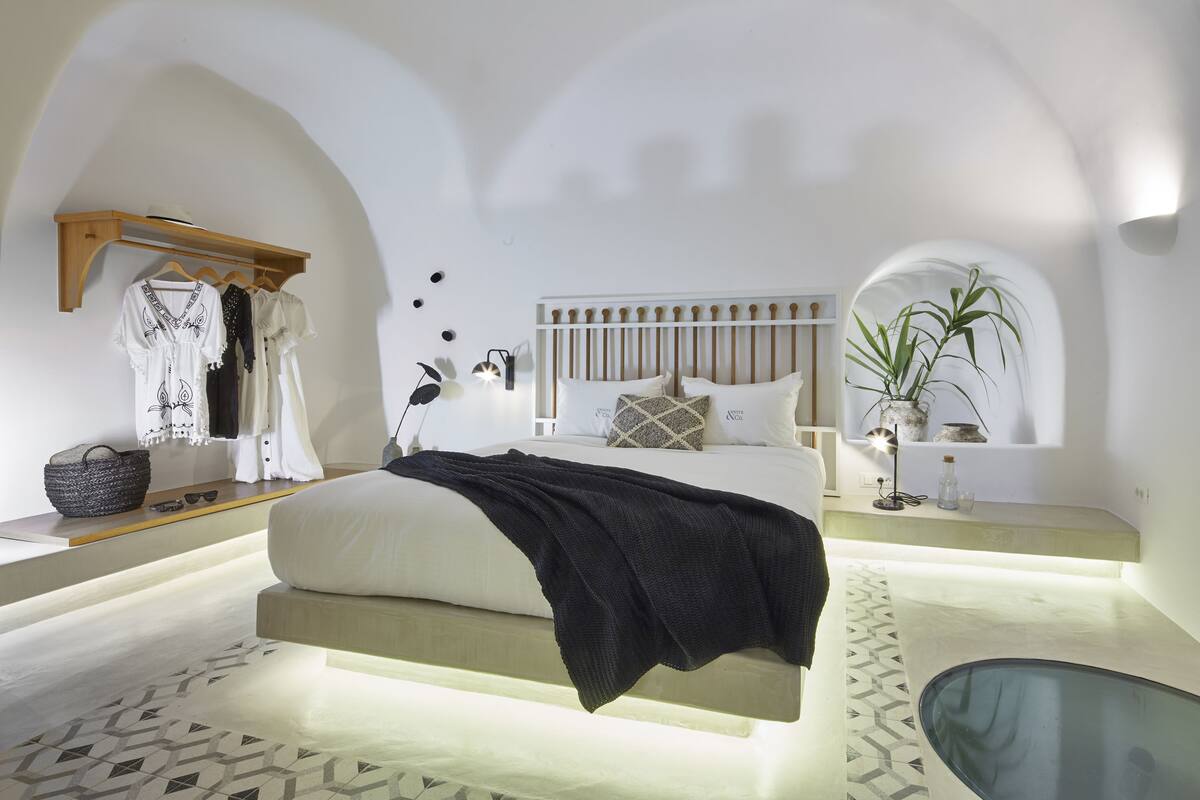 A modern bedroom with a bed, bedside tables, a hanging wardrobe, and a potted plant.