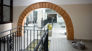 Un couloir intérieur doté d’une arche en briques, d’un sol carrelé et de rampes en métal.