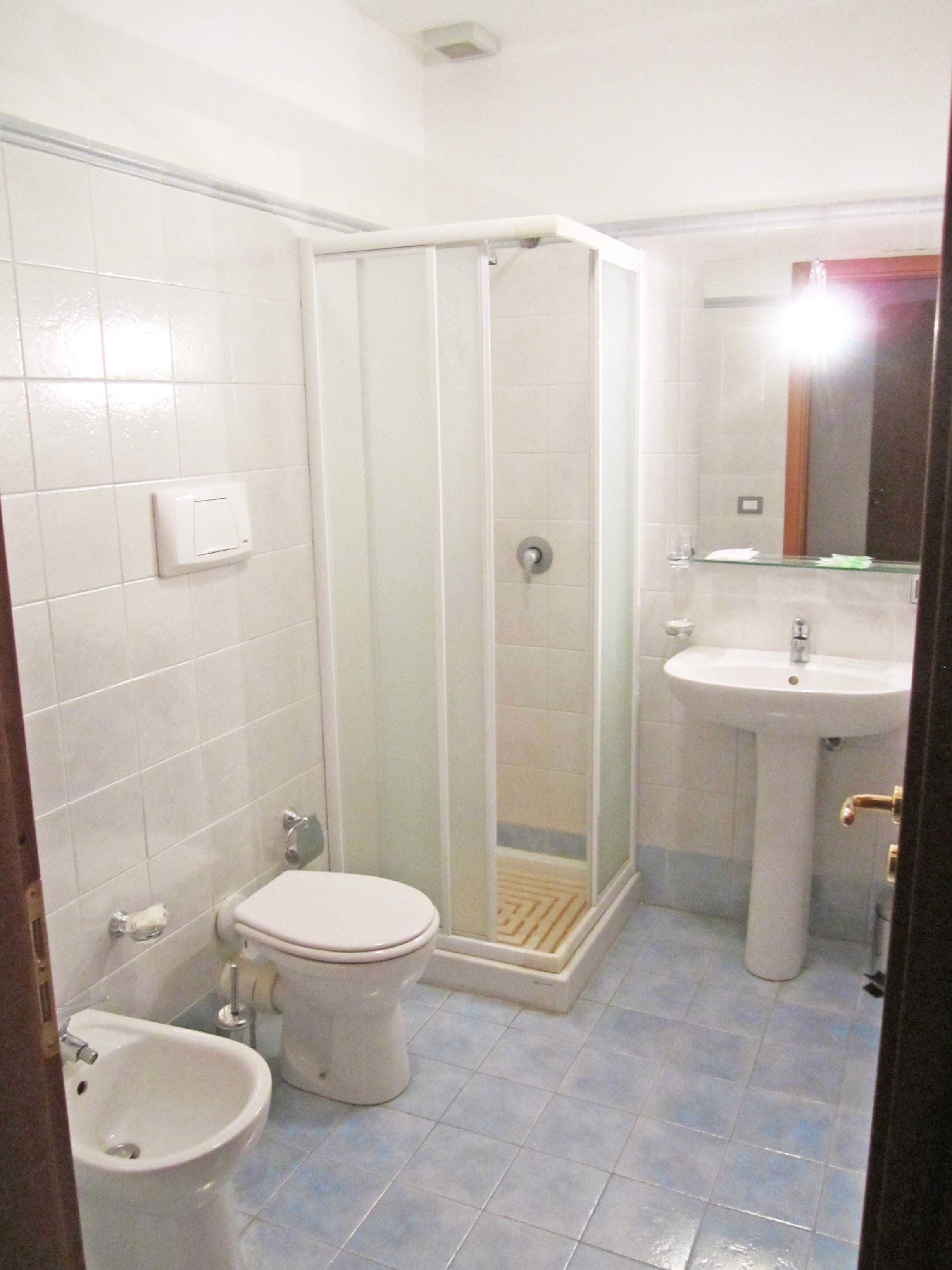 Ein Badezimmer mit Toilette, Bidet, Waschbecken und einer Duschkabine.