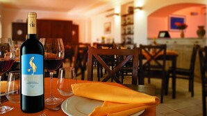 Une table à manger avec une bouteille de vin, des verres et une serviette.
