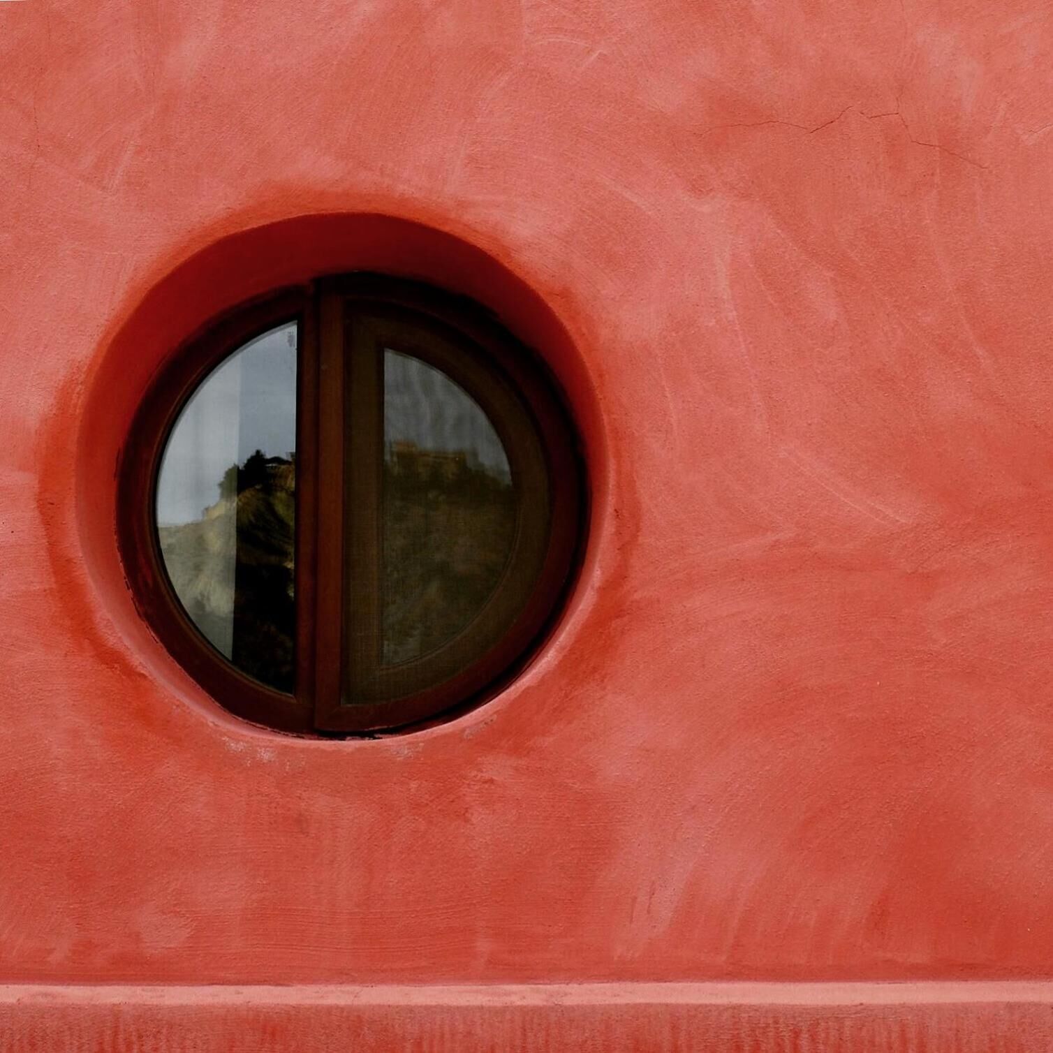 A circular window with a reflection of a building.