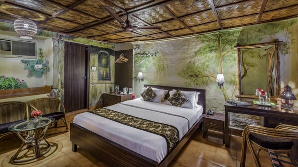 A room with a bed, a desk, a chair, a table, and a ceiling fan. - Sunderban Tiger Camp (Gosaba)