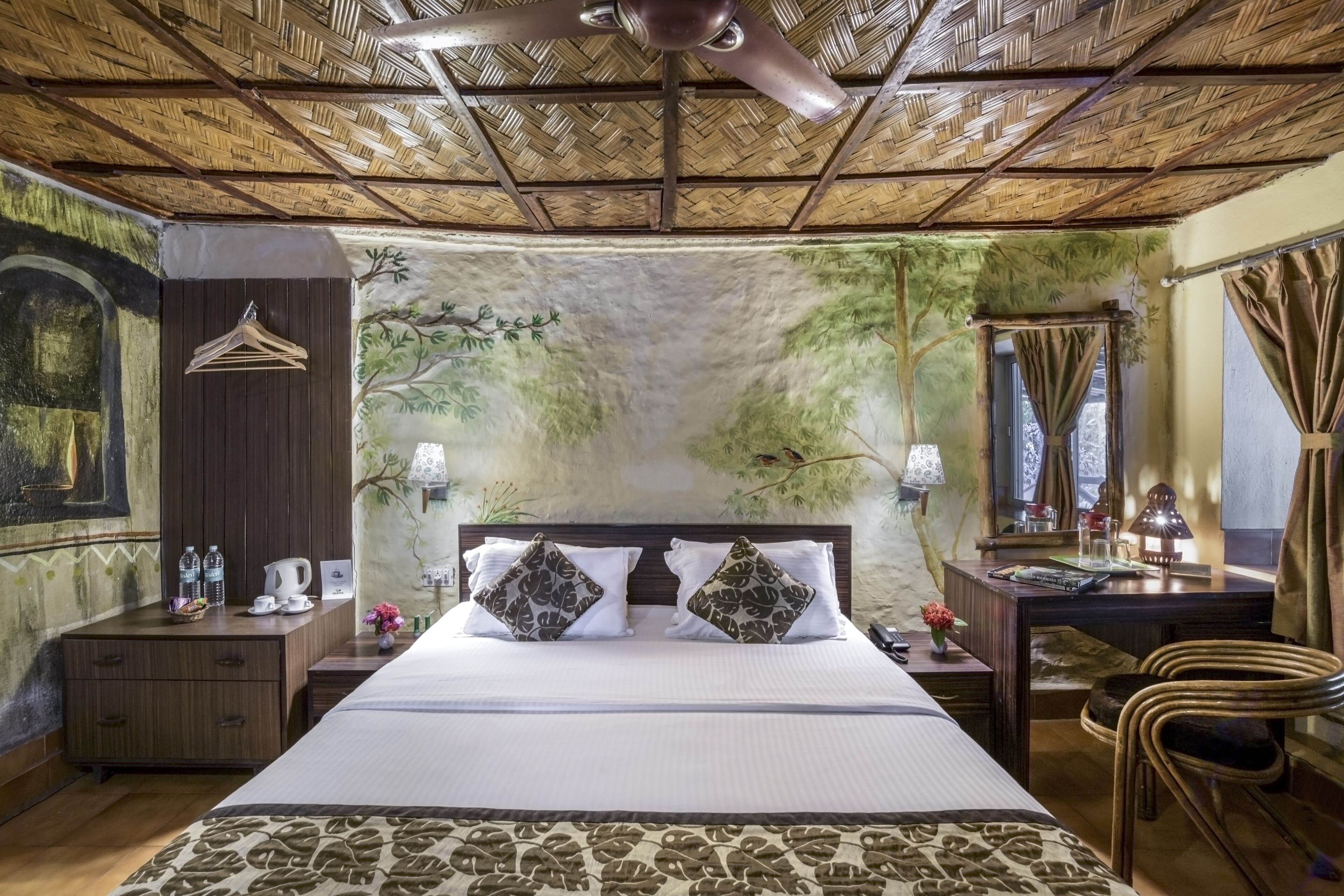 A bedroom with a bed, wooden headboard, a nightstand, a desk, a chair, a hanging clothes rack, and a ceiling fan.
