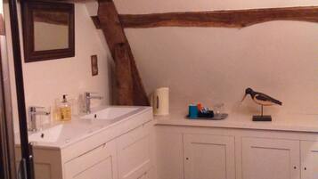 A bathroom with a wooden beam ceiling, white cabinets, and a double sink.