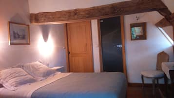 Ein Schlafzimmer mit einem Bett, einer Holztür, einem Sessel und zwei gerahmten Bildern an der Wand.
