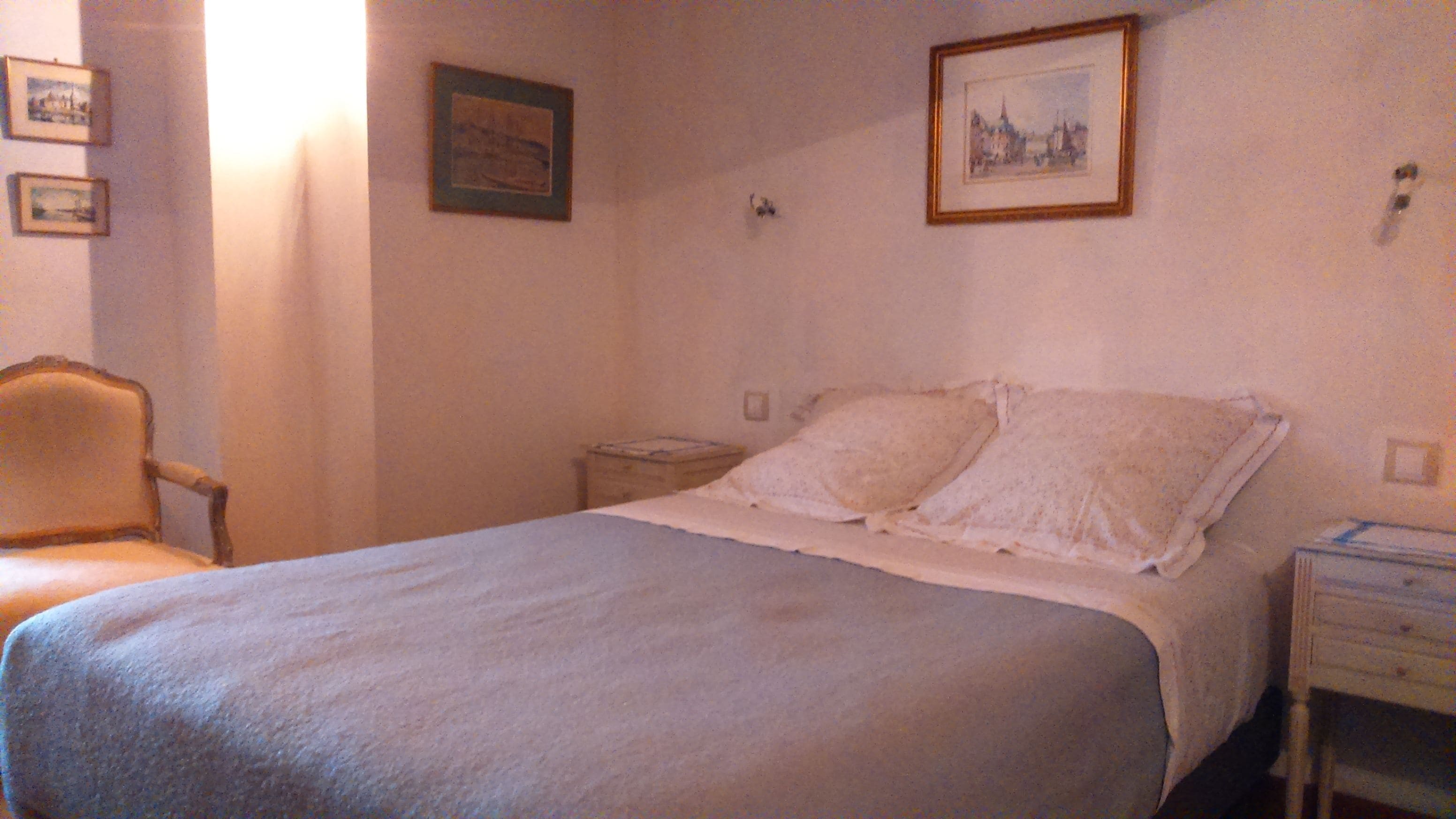 Un dormitorio sencillo con una cama, una silla y dos mesitas de noche.
