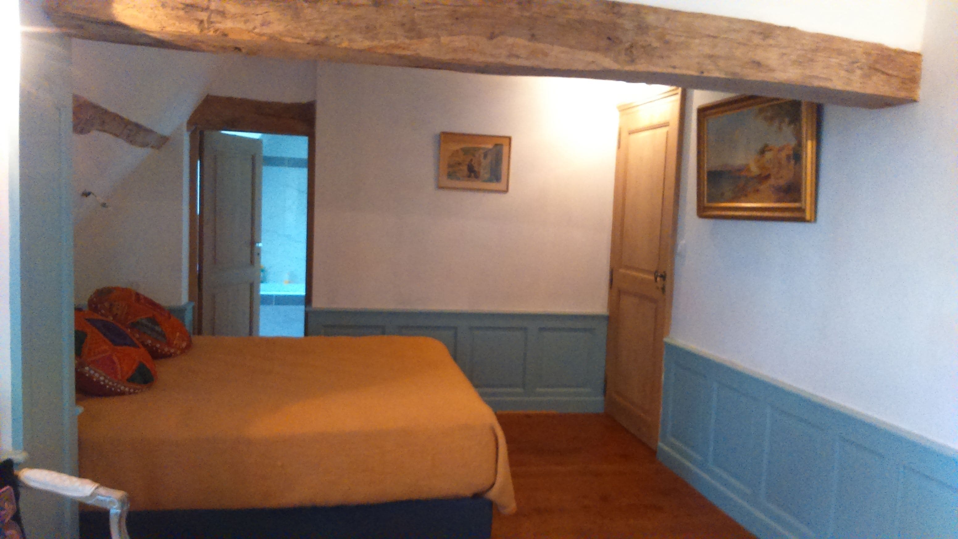 Une chambre à coucher avec un lit, une porte, un tableau et une fenêtre.
