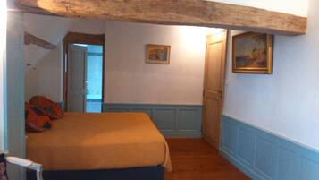 Une chambre à coucher avec un lit, une porte, un tableau et une fenêtre.