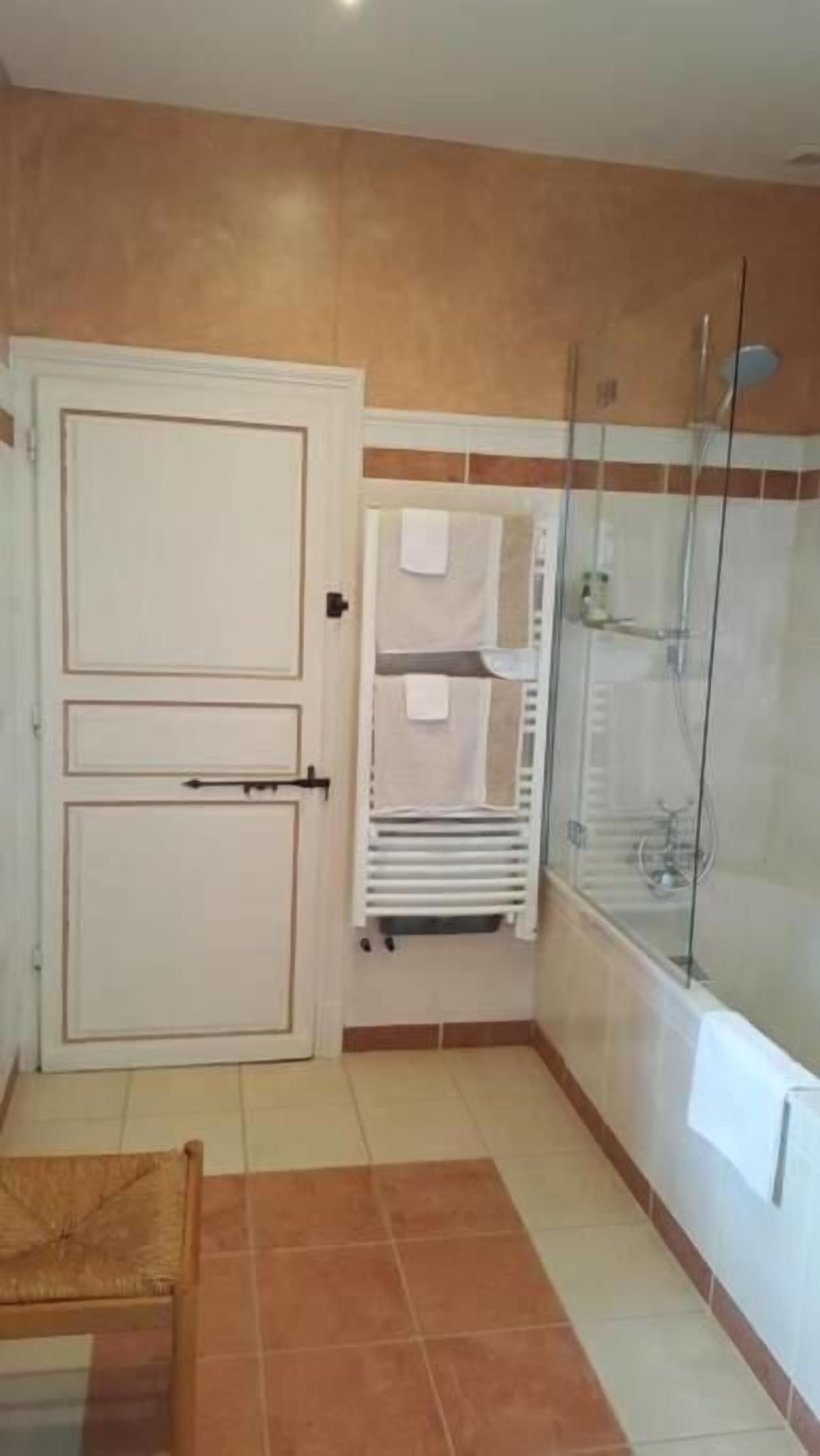 A bathroom with a shower, a towel rack, and a door.