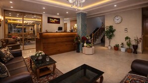 Un hall espacioso con una recepción, asientos cómodos, una escalera y plantas decorativas.