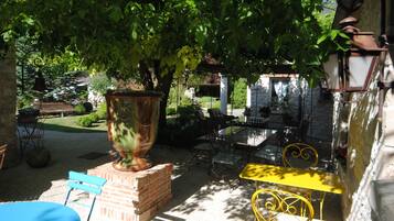 Un patio al aire libre con una mesa de ladrillo, sillas amarillas y una urna grande.