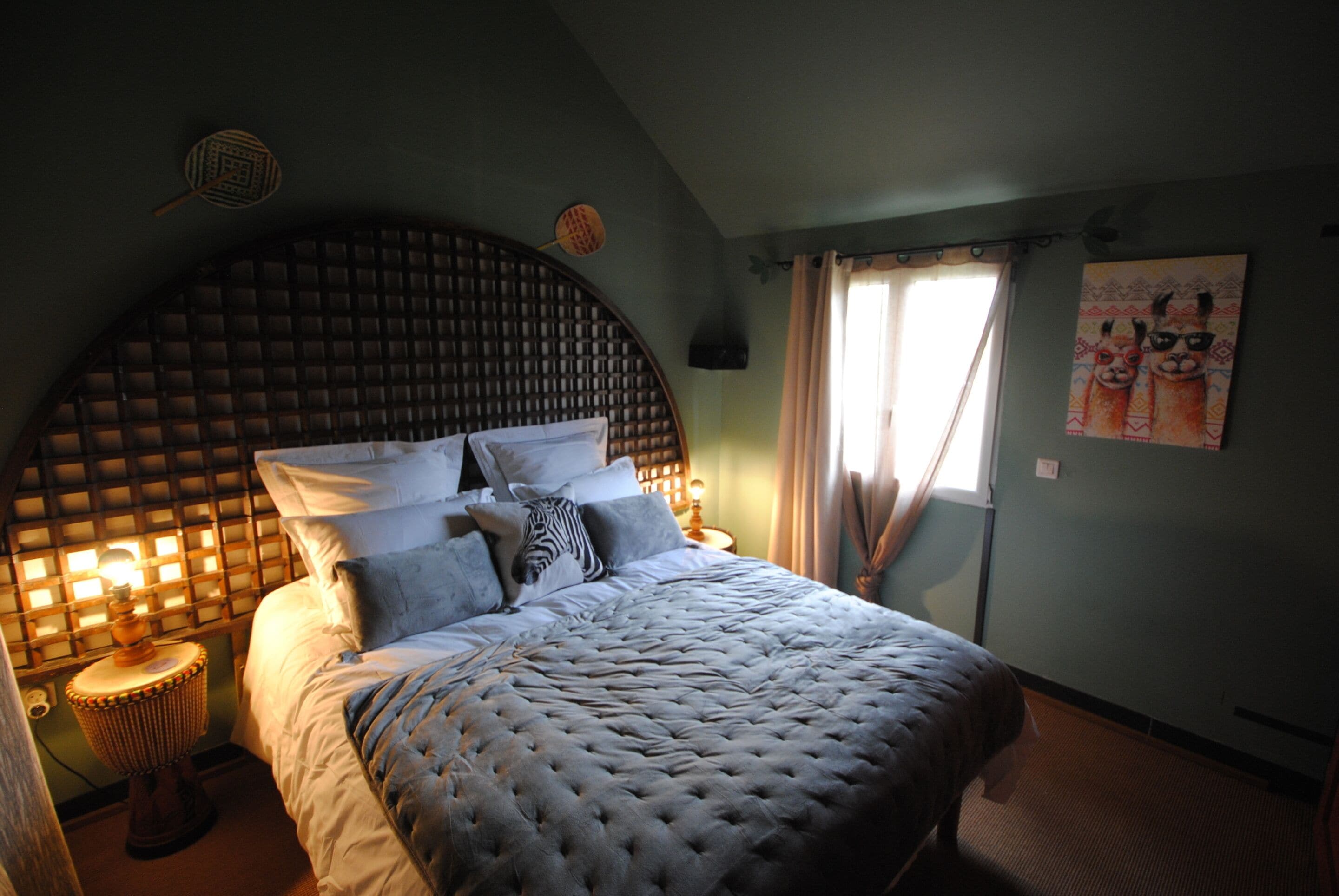 Een slaapkamer met een groot, gestoffeerd bed, een houten hoofdbord en een nachtkastje met een lamp.