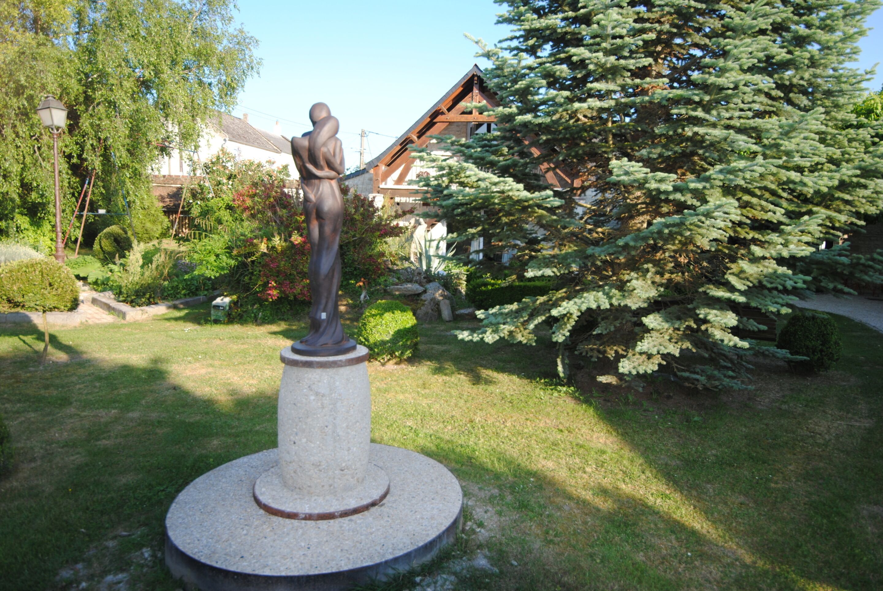 Ein Garten mit einer Statue, einem Holzhaus und einem großen Baum.