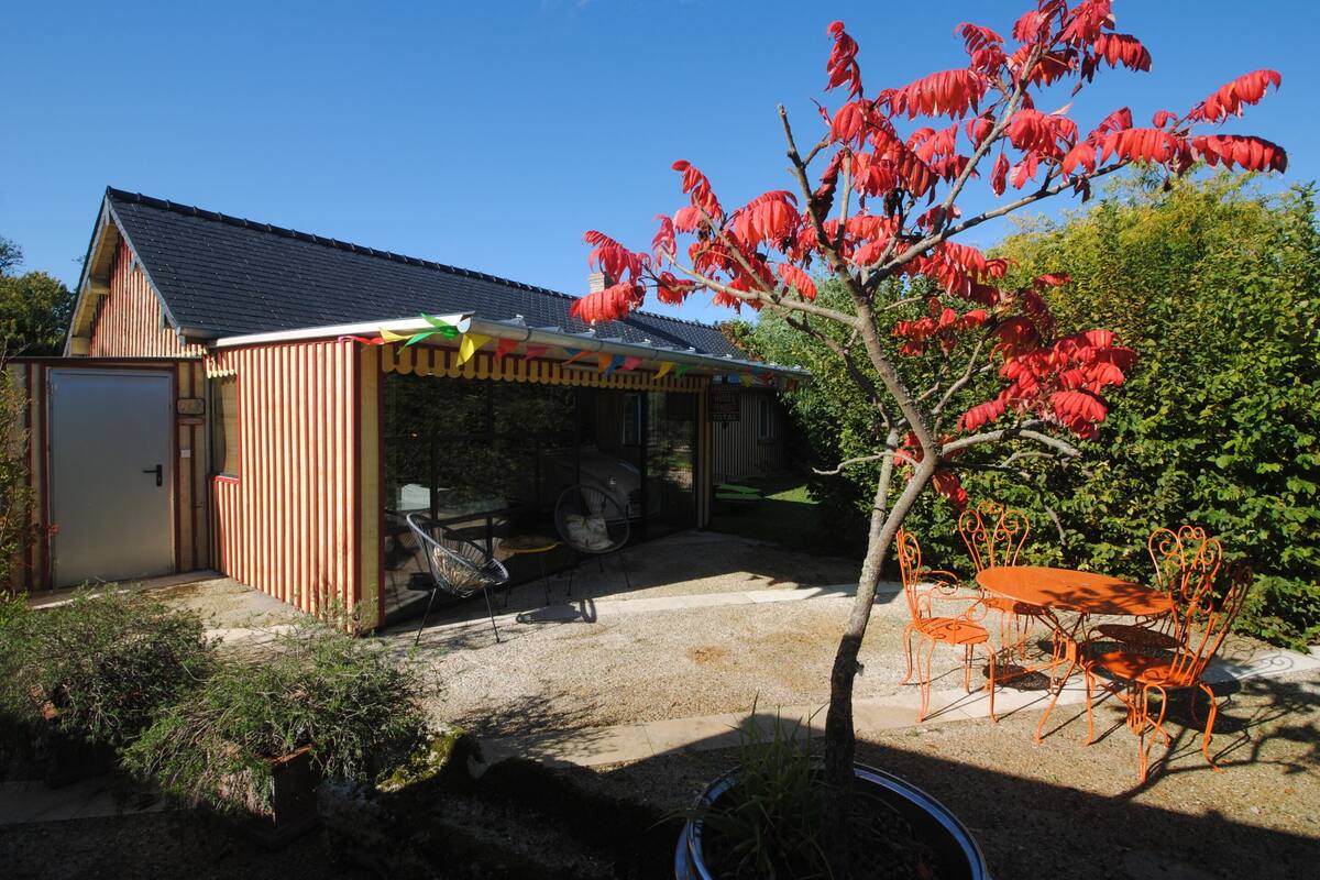 A covered outdoor area with a table and chairs, a bicycle, and a small shed.