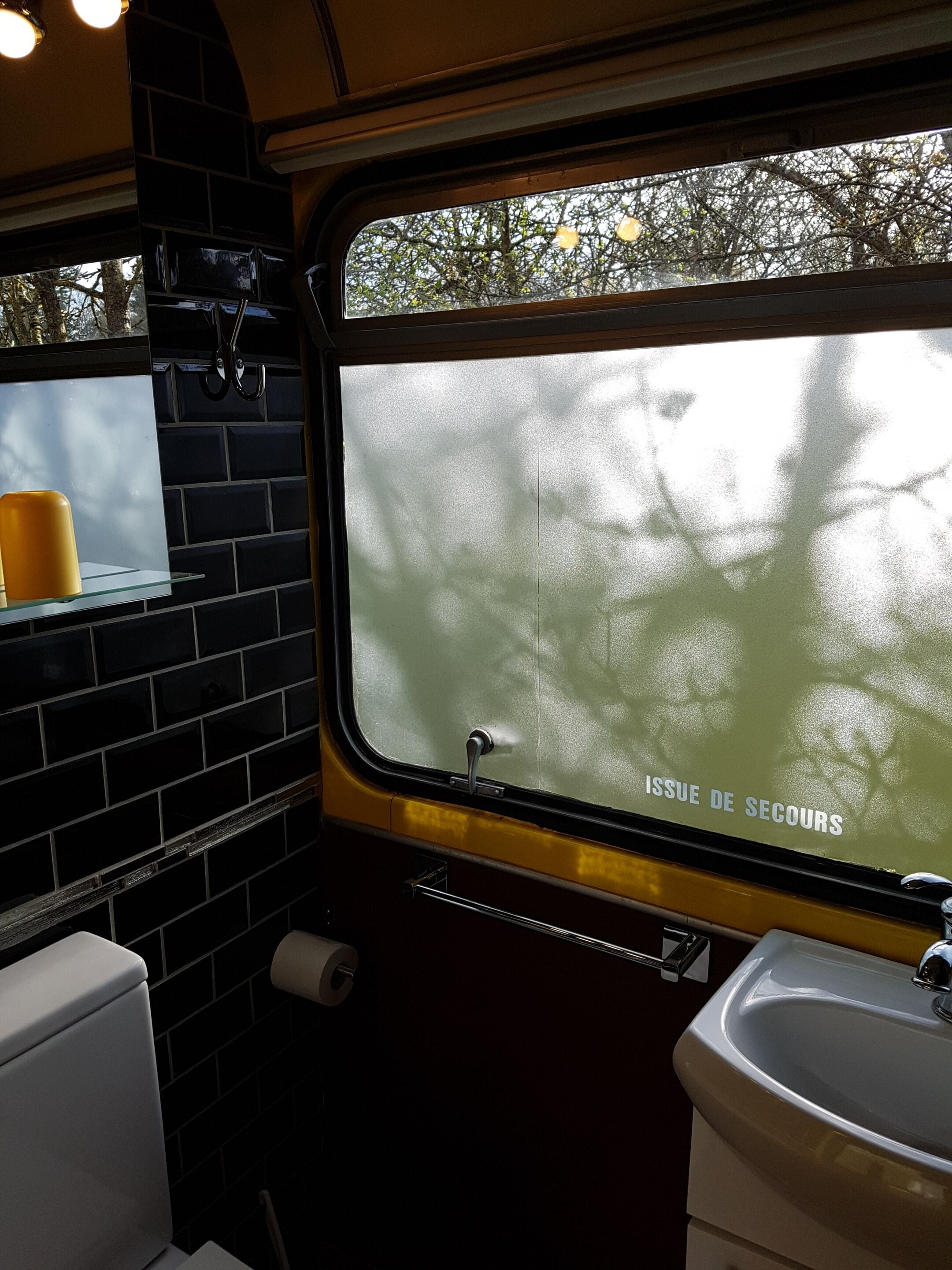 Een toilet in een treincabine met een toilet, wastafel en raam.