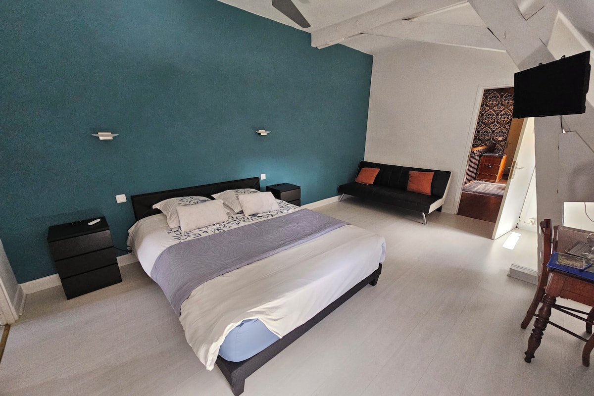 Ein Schlafzimmer mit einem Bett, einem Nachttisch, einer Kommode, einem Schreibtisch mit Stuhl und einem Fernseher.