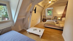 Une chambre mansardée chaleureuse, avec un lit, une petite table et un ventilateur de plafond.