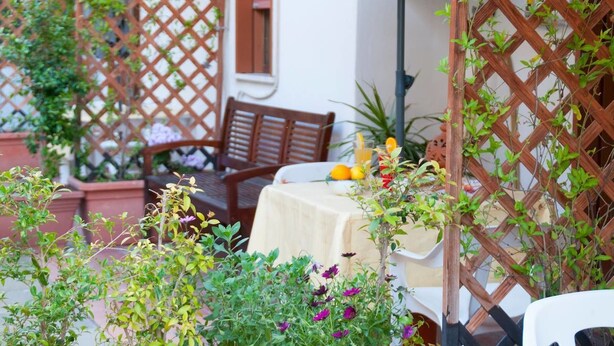 An outdoor seating area with a table, chairs, and potted plants. - B&B Sikily Naxos (Giardini Naxos)