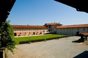 A courtyard with a building featuring a tiled roof and a central lawn area. - Agriturismo Camisassi (Saluzzo)