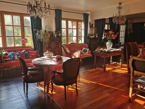Een gezellige woonkamer met houten vloer, een eettafel, een bank en een kroonluchter.