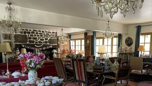 A spacious room with a fireplace, multiple chandeliers, and antique furniture. - Hôtel bar b’rock (Saint-Martin-sous-Vigouroux)