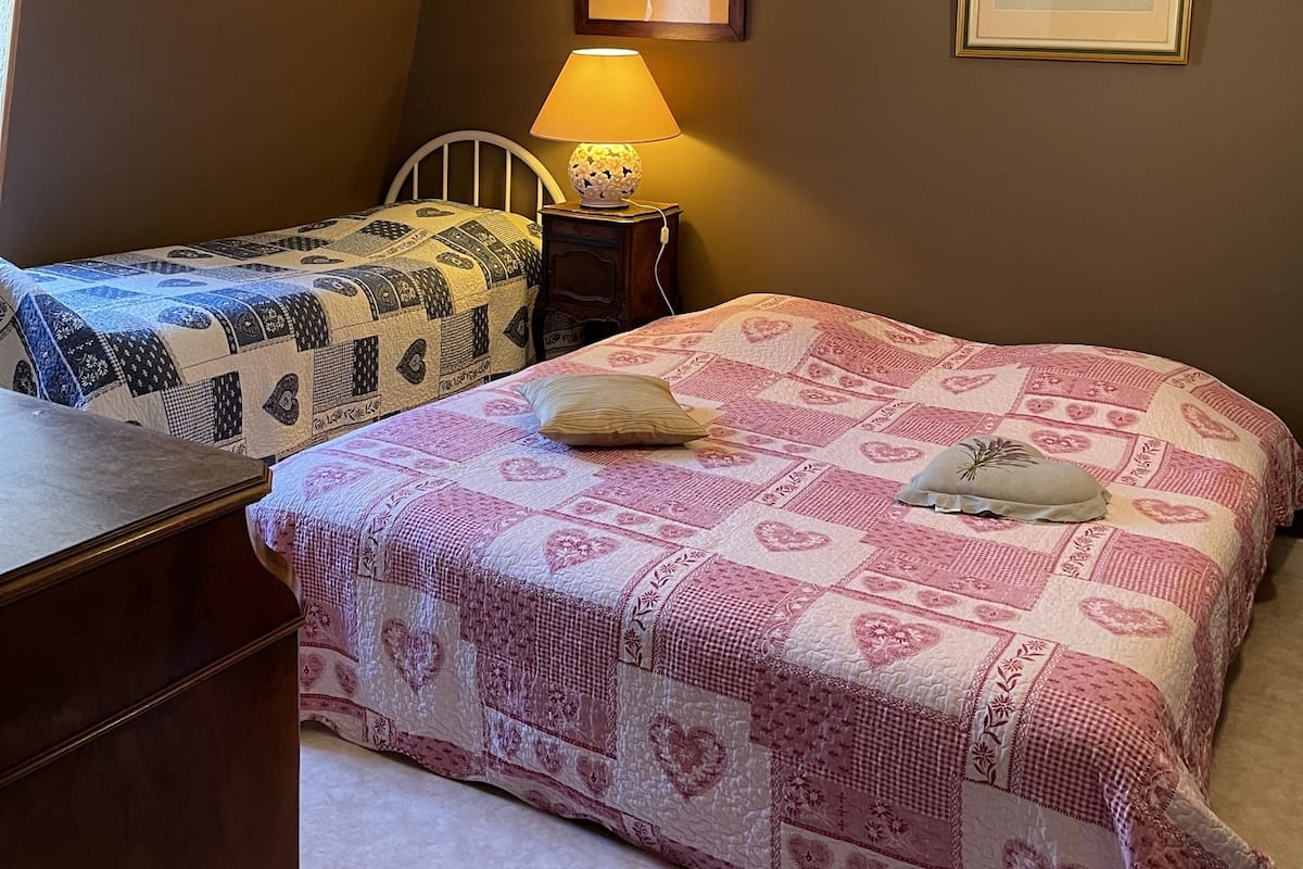 Ein Schlafzimmer mit zwei Betten, einem Nachttisch, einer Lampe und zwei gerahmten Bildern an der Wand.