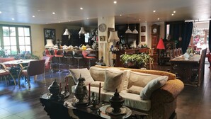 A spacious living area with a sofa, dining table, and chairs. There are decorative items on the coffee table, and a kitchen area is visible in the background. - Hôtel bar b’rock (Saint-Martin-sous-Vigouroux)