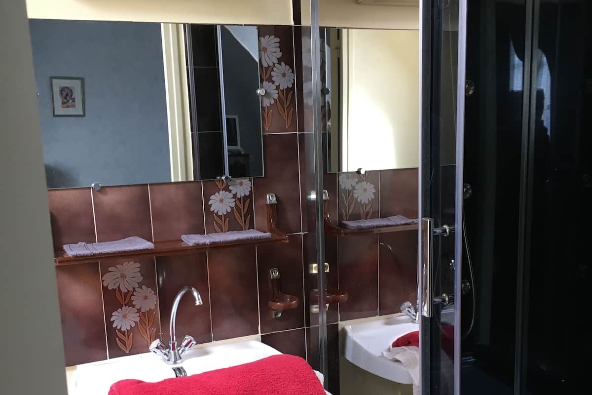 Ein Badezimmer mit zwei Waschbecken, einem roten Handtuch und einer Duschkabine aus Glas.