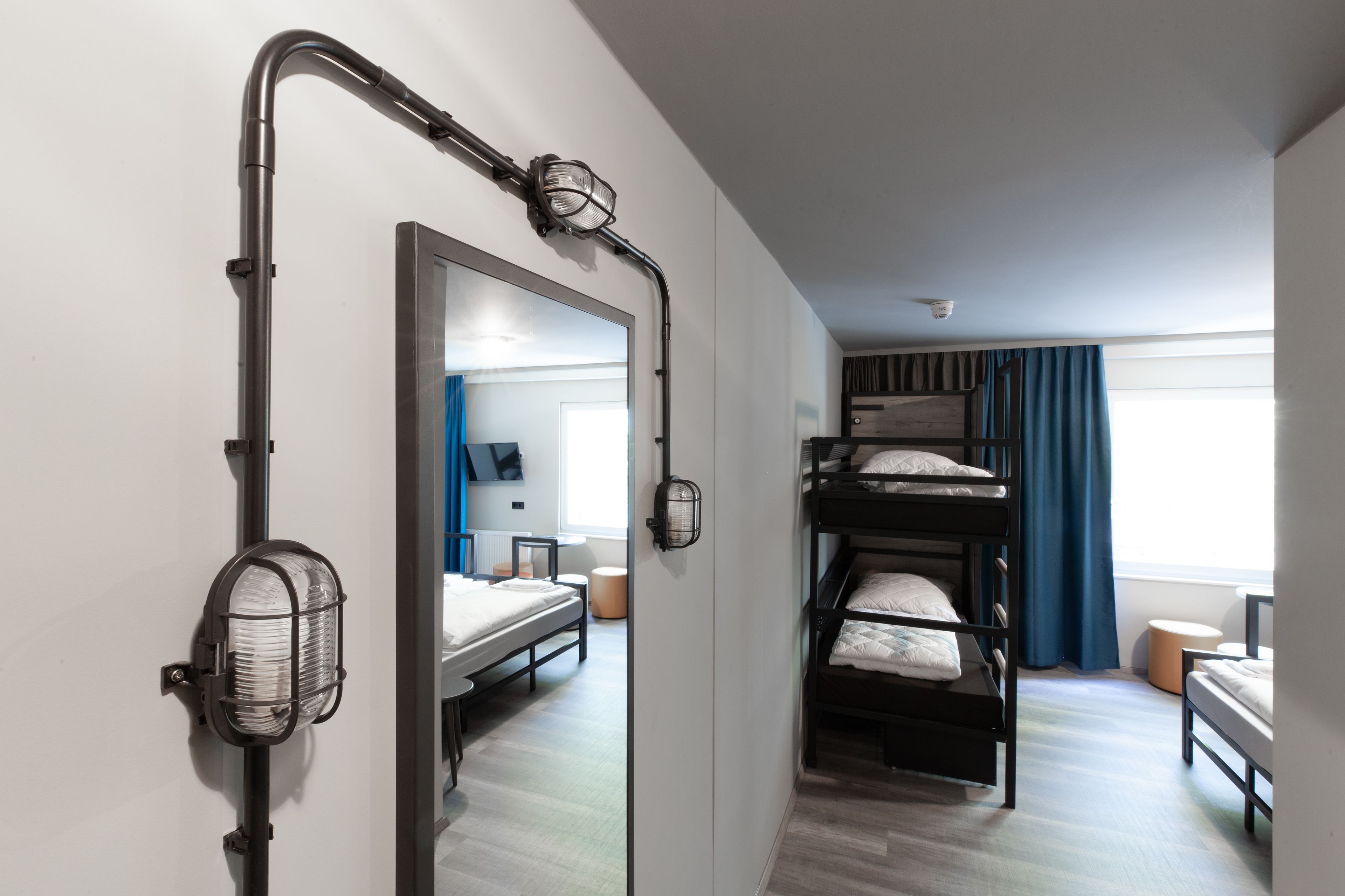 A modern hotel room with bunk beds, a large mirror, and a unique lighting fixture.