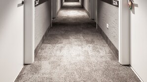 Un long couloir étroit d’hôtel, avec les portes numérotées 324 et 347.