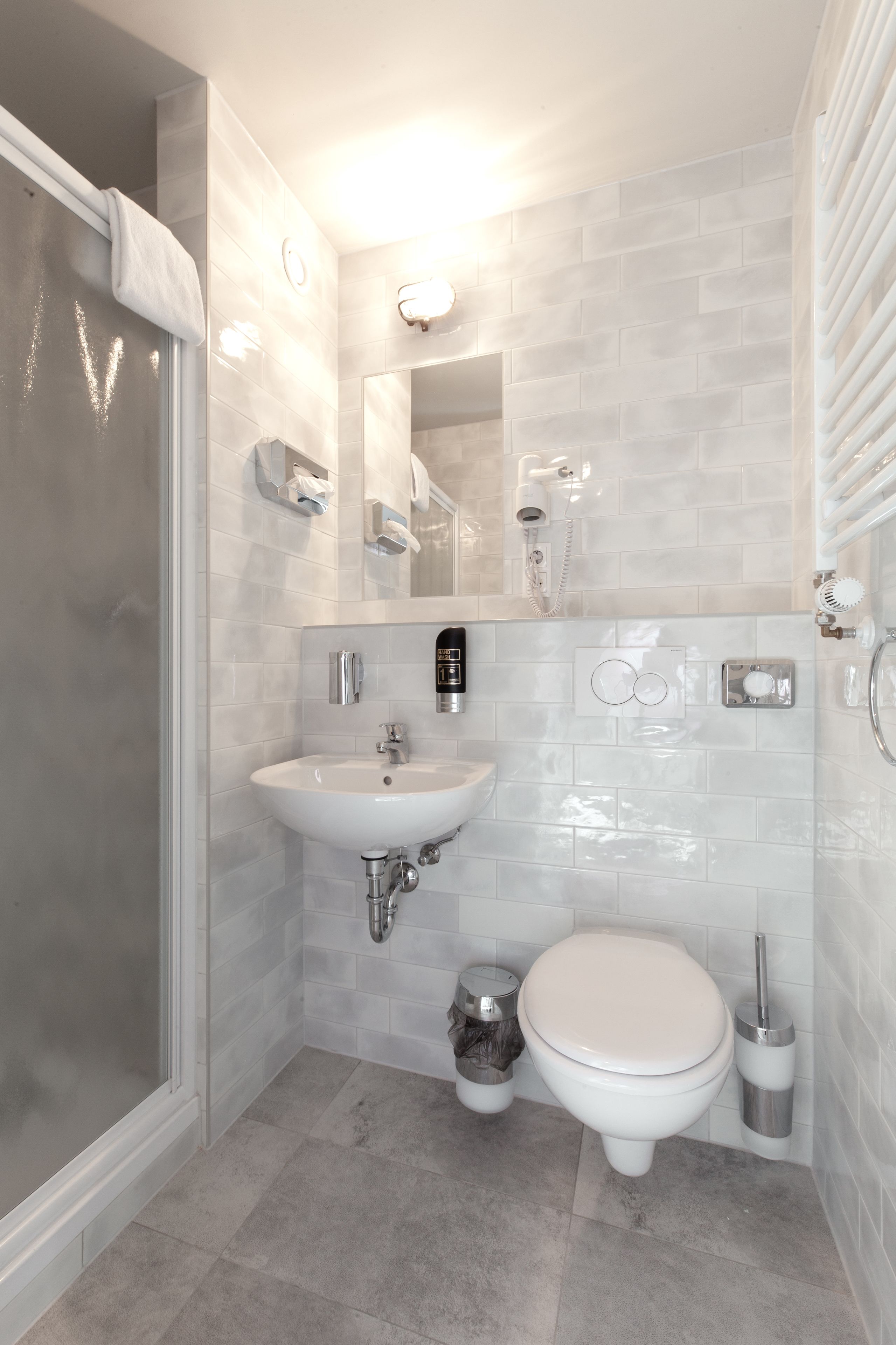 A modern bathroom with a glass shower enclosure, a white sink, and a toilet.