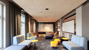 Un hall d’hôtel moderne, doté d’espaces aménagés avec des sièges, d’une cheminée et d’une grande fenêtre.