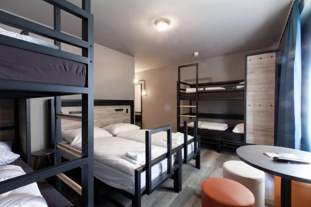 Une chambre avec des lits superposés, une table ronde et un tabouret.