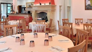A restaurant with round tables, wooden chairs, a red accent wall, and a fireplace. - Residence Gli Ulivi (Leverano)