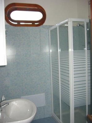 A bathroom with a white sink, a mirror, and a glass shower enclosure. - Residence Gli Ulivi (Leverano)