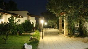 A paved pathway leading to a building with a white facade and wooden beams. - Residence Gli Ulivi (Leverano)