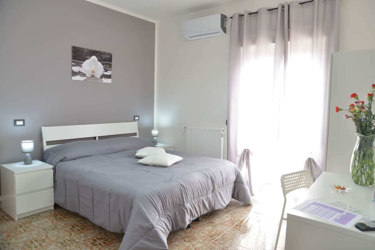 A bedroom with a bed, nightstands, a desk, and a chair.