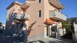 A two-story building with a flat roof, a gated entrance, and a small balcony on the upper floor. - Bellatrix (Portici)