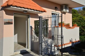 A building with a metal gate, a red-tiled roof, and a small air conditioning unit. - Bellatrix (Portici)