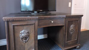 Un escritorio de madera oscura con un televisor de pantalla plana, dos cajones y tiradores decorativos.
