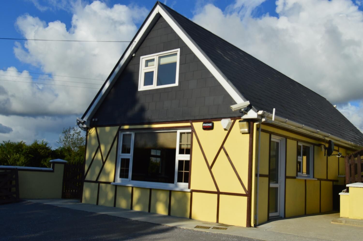 A single-story building with a gabled roof, a small porch, and a 'PHONE' sign.