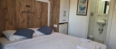 Una habitación de hotel con una cama, un archivador pequeño, un espejo y un cuadro en la pared.