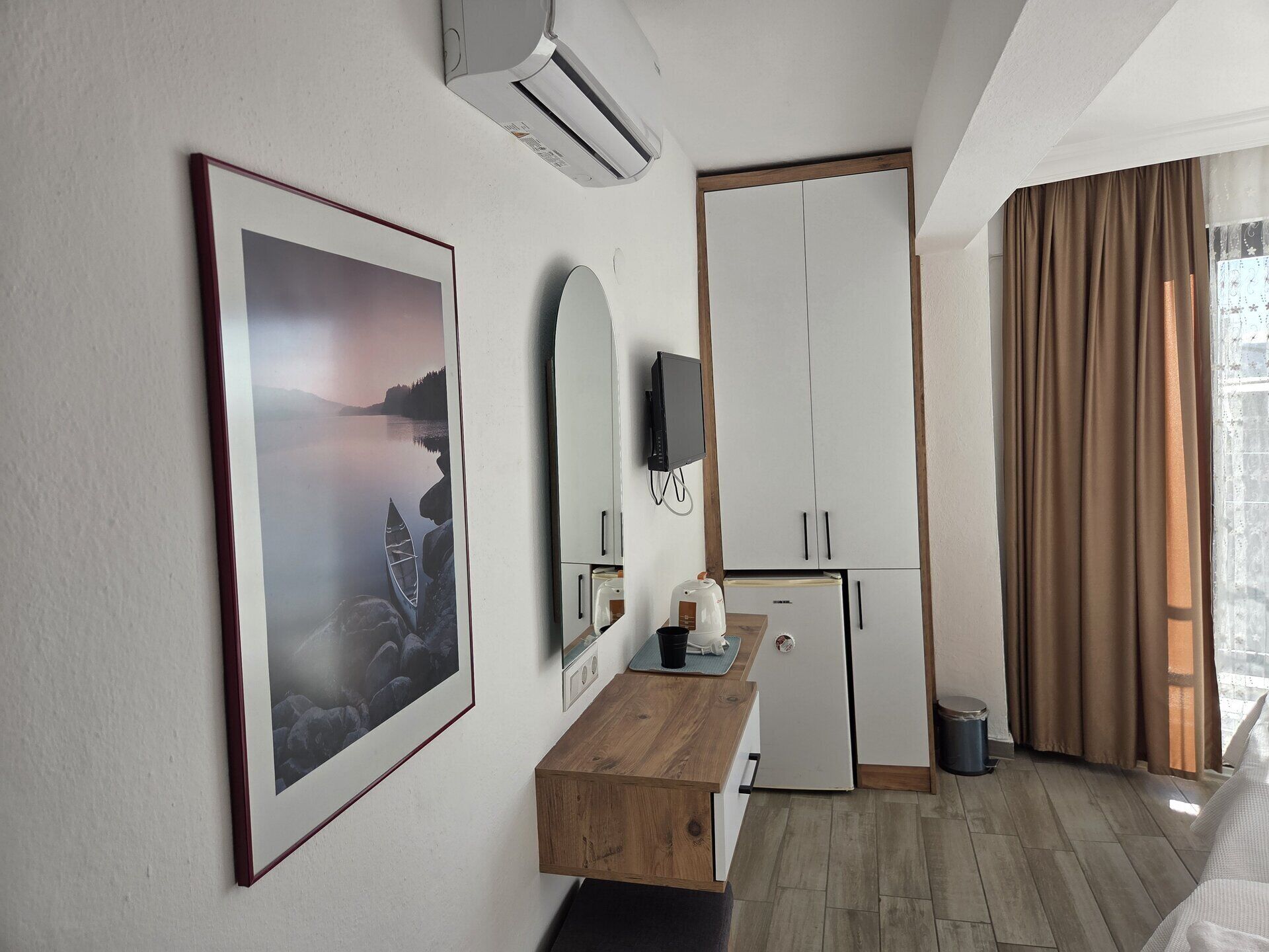 Ein Hotelzimmer mit einem Holztisch, einem Fernseher, einem Kleiderschrank und einem großen, gerahmten Bild an der Wand.